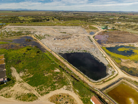 Aerial view of a large landfill site with a dark retention pond and surrounding rural landscape in Vredenburg, Western Cape, South Africa.