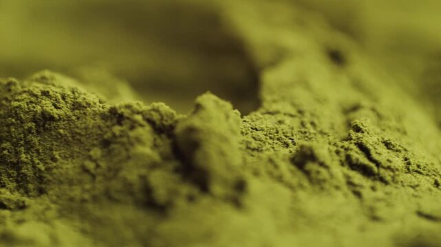 Green chlorella algae powder on a wooden spoon, top view. Healthy nutritional supplement.