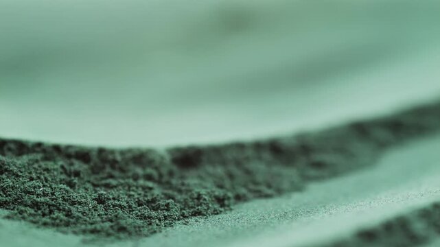 Green chlorella algae powder on a wooden spoon, top view. Healthy nutritional supplement.