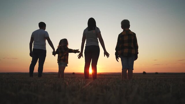 Family holding hands at sunset. Family, silhouette, holding, hands together, team, sunset, park. Team of football players together at the park at sunset. The photo is of a family lifestyle holding.