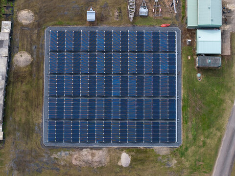 Aerial view of the solar powered waste water treatment plant featuring a grid of dark blue solar panels on a gravel base surrounded by grass in Byron Bay, New South Wales, Australia.