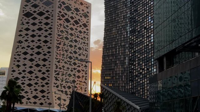 Low Angle Pan Of Modern Skyscrapers Silhouette Against Dramatic Golden Hour Sunset