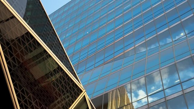 Dynamic Low Angle Pan Of Sky Reflections On Glass Facade Skyscrapers