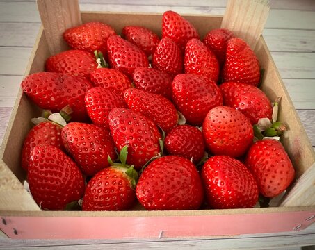 Fresas rojas y frescas recolectadas dentro de una caja de madera r&uacute;stica de madera listas para su consumo