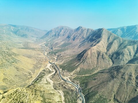 Aerial view of the Steel Bridge at Fort Munro winding through the rugged, arid terrain of the Sulaiman Mountains in Dera Ghazi Khan, Punjab, Pakistan.