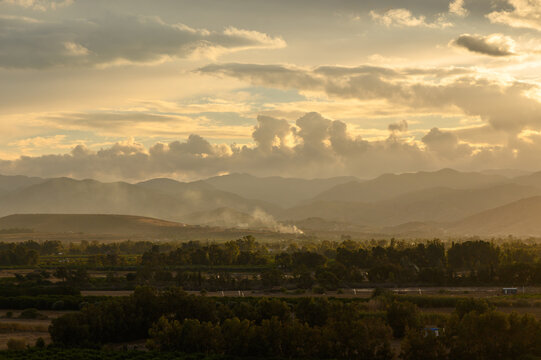 Majestic sunset casts golden hues over rolling hills and serene landscape in the evening light