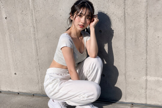 コンクリート壁際でしゃがむ女性