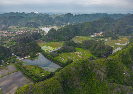 Aerial view of Tam Coc - Bich Dong featuring lush green karst mountains, winding rivers, and agricultural fields in Nam Hoa Lu, Ninh Binh, Vietnam.
