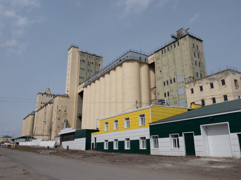Large concrete grain elevator building against a clear blue sky, industrial agricultural storage facility for grain processing and farming