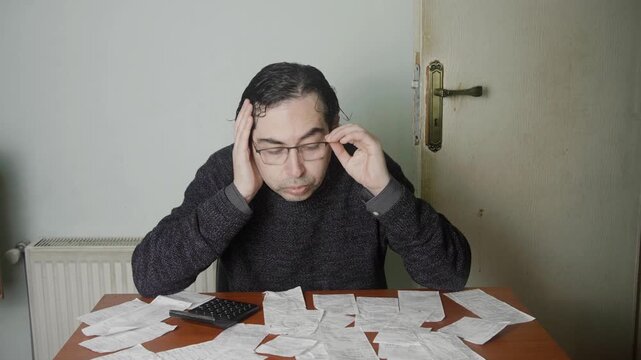 Mid Shot of Exhausted Man Taking Off Glasses While Auditing Piles of Receipts