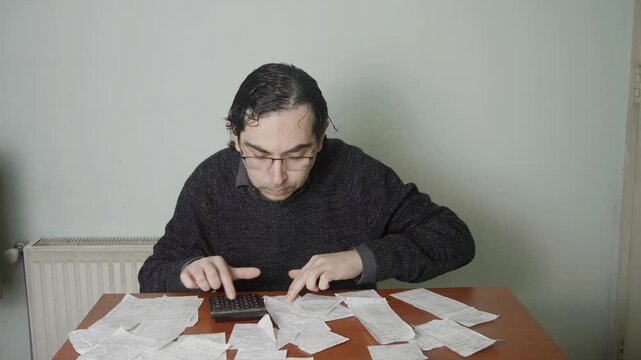 Depressed Caucasian Man Feeling Overwhelmed by Receipts and Debt at Desk