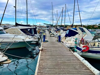 Pantalán de madera en un puerto deportivo con numerosos barcos y yates amarrados a ambos lados © GILPEDRO