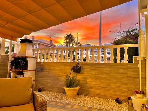 Patio exterior de una casa con barandilla y un espectacular cielo encendido durante el atardecer