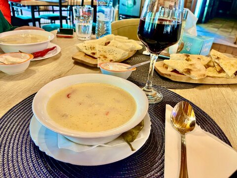 Cena tradicional en un restaurante con sopa caliente, pan plano y una copa de vino tinto