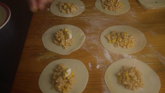 Chef Topping Homemade Empanada Stuffing with Sliced Eggs on Wooden Table