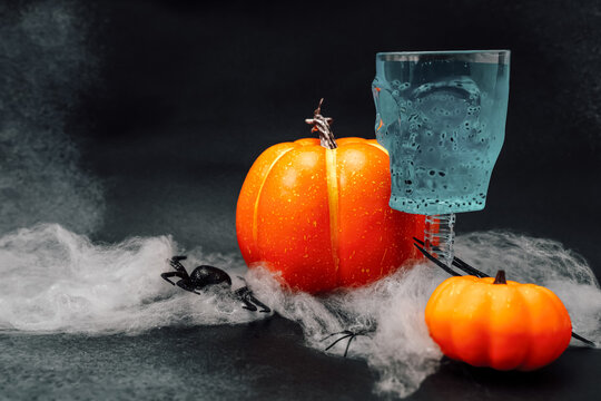 Halloween decorations with pumpkins spider and a ghost drink on a dark background