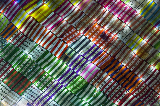 Aerial view of colorful fabric awnings arranged in a vibrant grid pattern, illuminated from below, in Kurigram, Rangpur Division, Bangladesh.