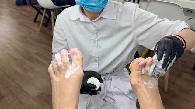 Pedicure hygiene: technician applying cleansing foam to toes, 16:9