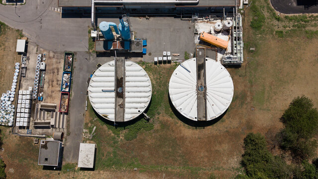 Aerial view of anaerobic digestion tanks at the Depuratore di Peschiera Borromeo sewage plant, showing wastewater treatment infrastructure in Peschiera Borromeo, Lombardy, Italy.