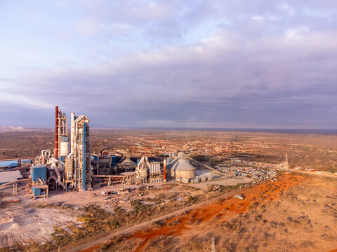 Aerial view of Simba Cement Merueshi factory with industrial structures, silos, and surrounding arid landscape under a cloudy sky in Kajiado, Kajiado County, Kenya.