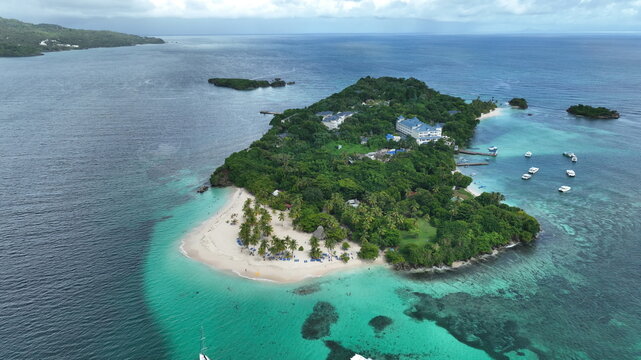 Aerial view of Cayo Levantado with its white sand beach, lush tropical vegetation, resort buildings, and turquoise waters in Samana, Dominican Republic.