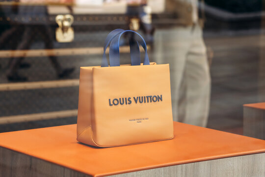 Monaco, Monaco - July 17, 2026: Orange Louis Vuitton shopping bag with blue handles displayed in a boutique window, marked &ldquo;Maison fond&eacute;e en 1854 Paris&rdquo; (&ldquo;House founded in 1854 Paris&rdquo;)