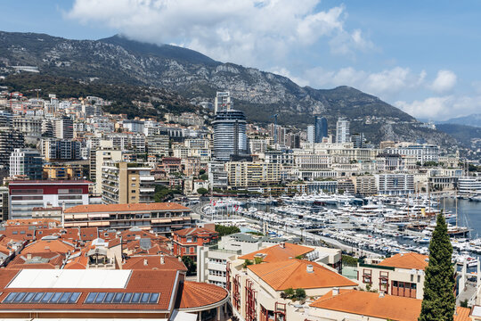 Monaco, Monaco - July 17, 2026: Panoramic view from Monaco Ville across La Condamine rooftops, Port Hercule marina and the Monte Carlo skyline beneath surrounding mountains
