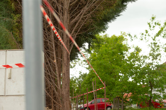 Red and white tape marking event boundary near trees and parked van blurred tape lines create sense of organized restriction and anticipatory atmosphere