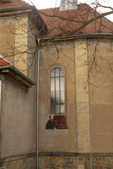 Narrow church alcove with tall arched window, textured brick sill and downpipe, subtle tree silhouette ideal for heritage architecture, urban exploration, © Viktar