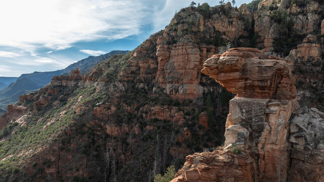 Aerial view of the iconic red rock formations in Sedona, featuring rugged sandstone cliffs, sparse green vegetation, and a clear blue sky in Sedona, Arizona, United States.