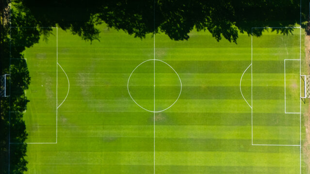 Aerial view of a soccer field with vibrant green grass and white pitch markings, bordered by lush trees in Leeuwarden, Friesland, Netherlands.