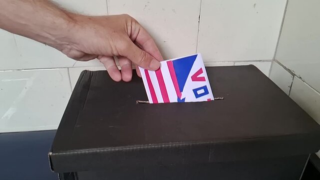 Person casting vote in ballot box for democratic election