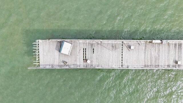 Aerial view of the weathered wooden planks of the Flagler Beach Pier extending into the Atlantic Ocean, showing structural details and textures in Flagler Beach, Florida, United States.
