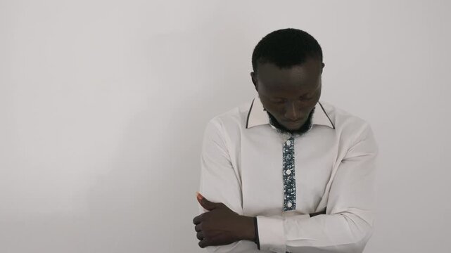 Nervous man in white shirt waiting. Black man prepares for romantic date, alternating roles as anxious suitor and busy businessman arms crossed, downward glances, tight collar and patterned tie, plain