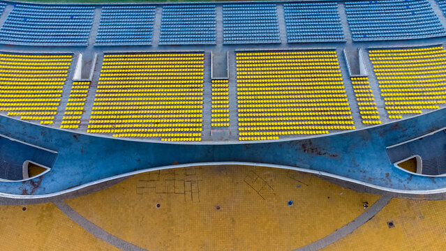 Aerial view of Cape Coast Sports Stadium featuring vibrant yellow and blue seating sections arranged in tiered rows, Cape Coast, Central Region, Ghana.