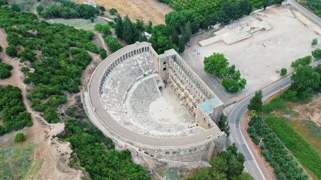 Aerial view of the ancient Roman amphitheater in Aspendos, Antalya, showcasing one of Turkey's most famous historical landmarks. Majestic drone shot over well-preserved stone ruins.