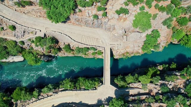 Aerial view of the historic stone bridge at Koprulu Canyon in Antalya, showcasing the ancient architecture over the deep river valley. Majestic drone flight in Manavgat, Turkey.