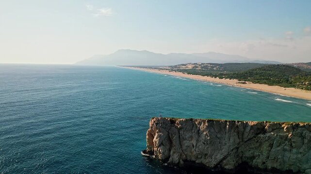 Man exploring rocky hills aerial view near Patara beach in Antalya Turkey. Drone shot capturing an adventurer walking on a rugged cliff overlooking the Mediterranean sea.