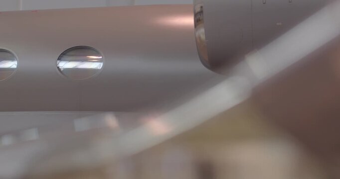 Row of cabin windows on fuselage profile closeup showing oval portholes, polished skin and soft hangar lighting during cabin outfitting and surface inspection. Emphasis on contours