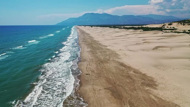 Antalya Patara beach aerial view showcasing golden sand dunes and turquoise sea. Spectacular drone footage over the famous Turkish Riviera coastline in full daylight.