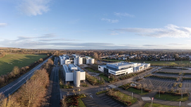 Aerial view of New College Durham, University white office buildings, parking lots, and surrounding green fields in Durham, England, United Kingdom.