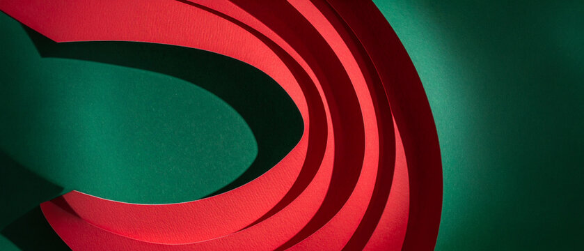 Paper shapes in red contrast with a background of green. Curves create shadow elements. Texture of paper builds structure for design. Geometry brings depth to the composition. Arts for backdrop spaces