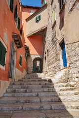 Obraz premium Narrow stone staircase between historic colorful buildings in Rovinj, Croatia.