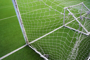 Green field behind broken sports netting Soccer Goal Net Set Against New Turf Field. white soccer net, set against newly laid green synthetic turf field. Overhead stationary view. © Maxim Chuev