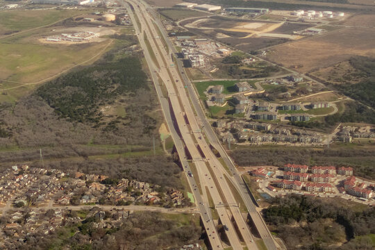 Aerial view of Highway 290 with power lines, apartment complexes, office buildings, and storage tanks outside of Austin, Texas in Travis County