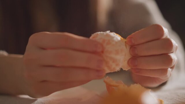 Closeup of fingers peeling orange rind carefully. Detailed view of fingertips delicately removing bright orange peel. Close examination of hands gently stripping vibrant citrus peel from fruit