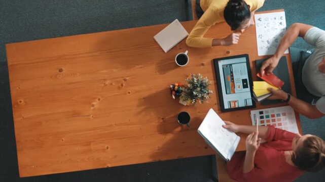 Top aerial view of business people working together to choosing color from color palette. Manager present idea by using tablet to marketing team while business man looking at logo graphic. Symposium.