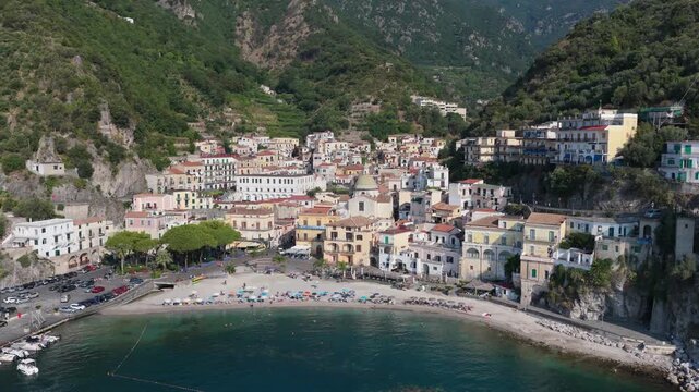 Aerial view of the coastal village of Cetara with its historic tower, sandy beach, colorful houses, and lush green mountains in Cetara, Amalfi Coast, Campania, Italy.