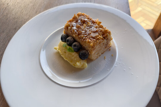 Napoleon cake piece with fresh blueberries on extra portion custard