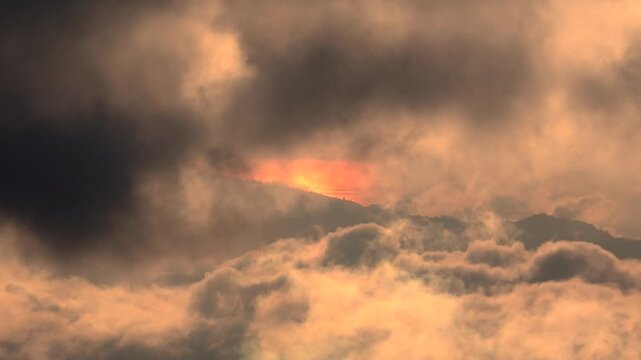 Thick black and red smoke covers forest hills during an intense wildfire disaster.